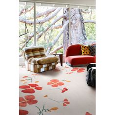 a living room filled with furniture next to a large glass window covered in red flowers