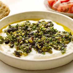 a white bowl filled with yogurt and garnished with toppings next to crackers