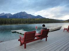 two red benches sitting on top of a wooden pier next to a body of water