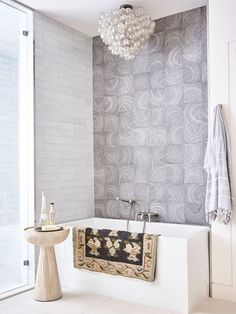 a bath tub sitting next to a white sink under a light hanging from a chandelier