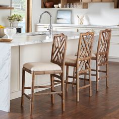 three wooden chairs sitting at the end of a kitchen counter