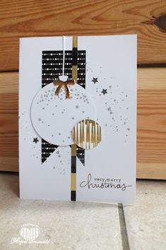 a white card with gold foil on it and a black ribbon hanging from the front