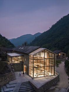 the building is lit up at night with stairs leading up to it and people walking around