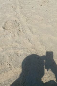 a shadow of a person riding a motorcycle on the beach