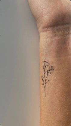 a small tattoo on the wrist of a woman's left arm with a single flower