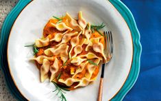 a white plate topped with tortellini shells and garnished with fresh herbs