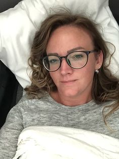 a woman laying in bed wearing glasses