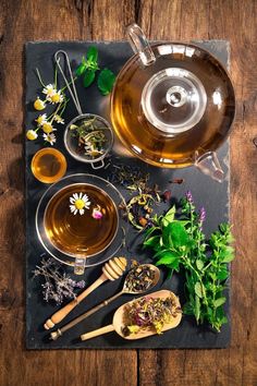 an assortment of herbs and tea on a slate board