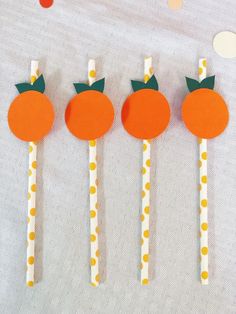 four oranges are sitting on top of paper straws with green leaves and polka dots