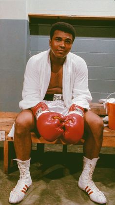 a man sitting on a bench wearing boxing gloves