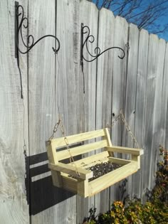 a bird feeder hanging from the side of a wooden fence