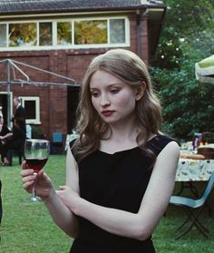 a woman in a black dress holding a glass of wine