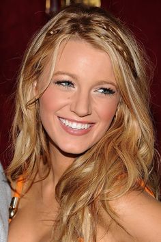 a beautiful blond woman with blue eyes and blonde hair smiling at the camera while wearing an orange dress