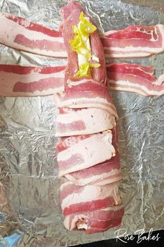 bacon wrapped in aluminum foil with a yellow flower on the end, and another piece of meat that has been cut into smaller strips