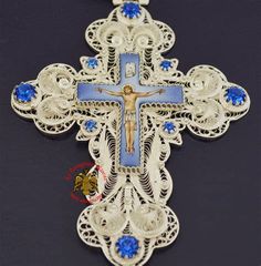 the cross is adorned with blue stones and filigrees on a black surface