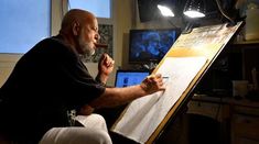 an older man sitting in front of a white board with writing on it while holding a pencil