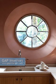 a round window in the wall above a sink