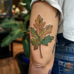 a woman's arm with a leaf tattoo on it