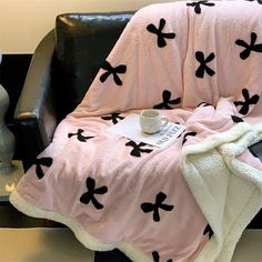 a black and white chair with a pink blanket on it next to a coffee cup