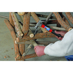 a person is using a pair of scissors to cut wood sticks into small structures that are stacked on top of each other