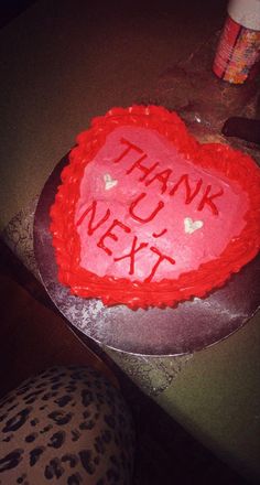 a heart shaped cake with the words thank next written on it in red frosting