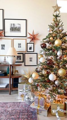 a decorated christmas tree with gold and silver ornaments in front of pictures on the wall