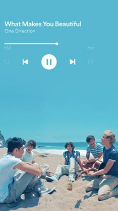 a group of people sitting on top of a sandy beach next to the ocean with headphones in their ears