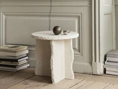 a small table with an apple on top of it next to books and a vase