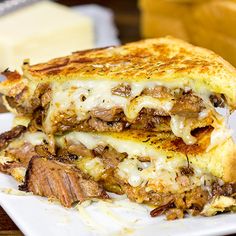 a close up of a sandwich on a plate with cheese and meat in the background