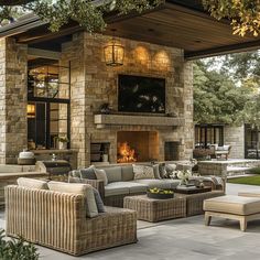 an outdoor living area with wicker furniture and stone fireplace