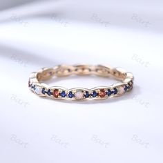 a gold ring with blue, red and white stones on the inside is sitting on a white surface