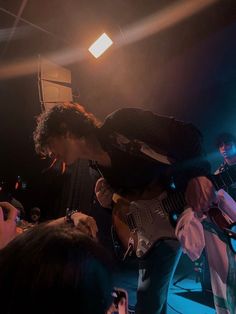 a man playing an electric guitar in front of a group of people at a concert