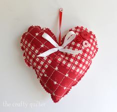 a red and white heart shaped ornament hanging on a wall