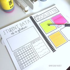 a student's workbook on a desk with pens and sticky notes next to it