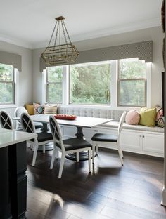 a dinning room table with four chairs and a bench in front of the window