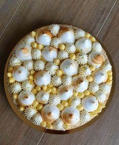 a cake with white and yellow toppings on a wooden table next to a knife