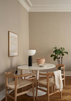 a white table with two chairs and a vase on it next to a potted plant