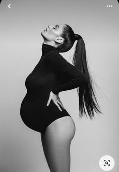 black and white photo of pregnant woman in tight bodysuit posing with her hands on her hips