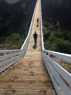 two people walking across a wooden bridge