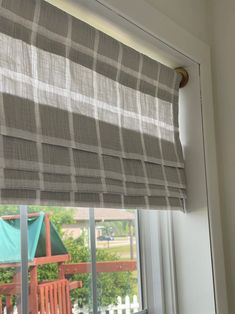 an open window with a checkered roman blind