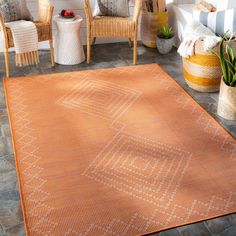 an orange area rug on the patio with chairs and potted plants in the background