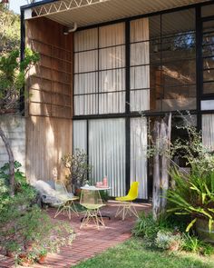 an outdoor patio with yellow chairs and table in front of the house's sliding glass doors