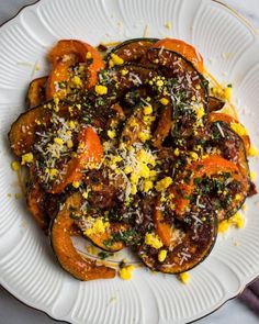 a white plate topped with cooked vegetables on top of a table