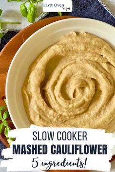 a bowl filled with mashed cauliflower on top of a wooden cutting board