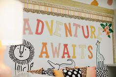 there is a sign that says adventure awaits on the wall next to some pillows