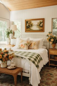 a white bed sitting in a bedroom next to a table with flowers on top of it