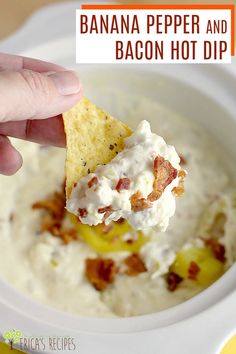 a hand holding a tortilla chip over a bowl of bacon hot dip