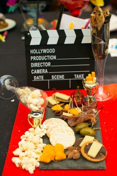 a red tray topped with cheese and crackers next to a movie clapper on top of a table