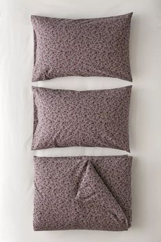 two pillows on top of each other in front of a white wall