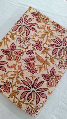 an orange and pink floral design on a white sheet